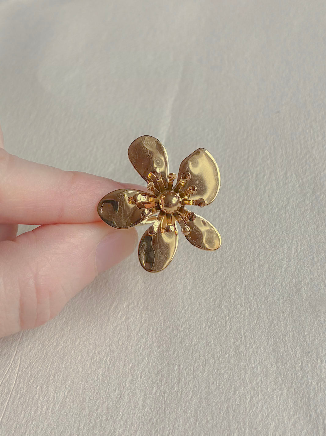 Vandfast forgyldt ring med blomst på hånden