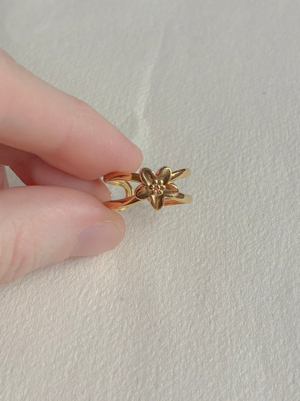 Vandfast forgyldt ring med lille blomst på hånden