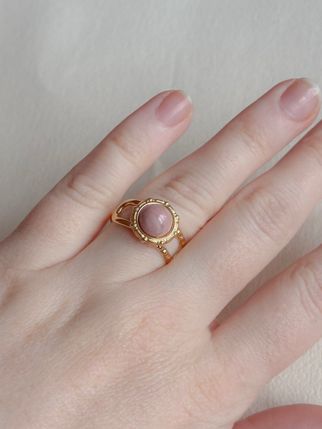 Vandfast forgyldt ring med rosa sten på hånden